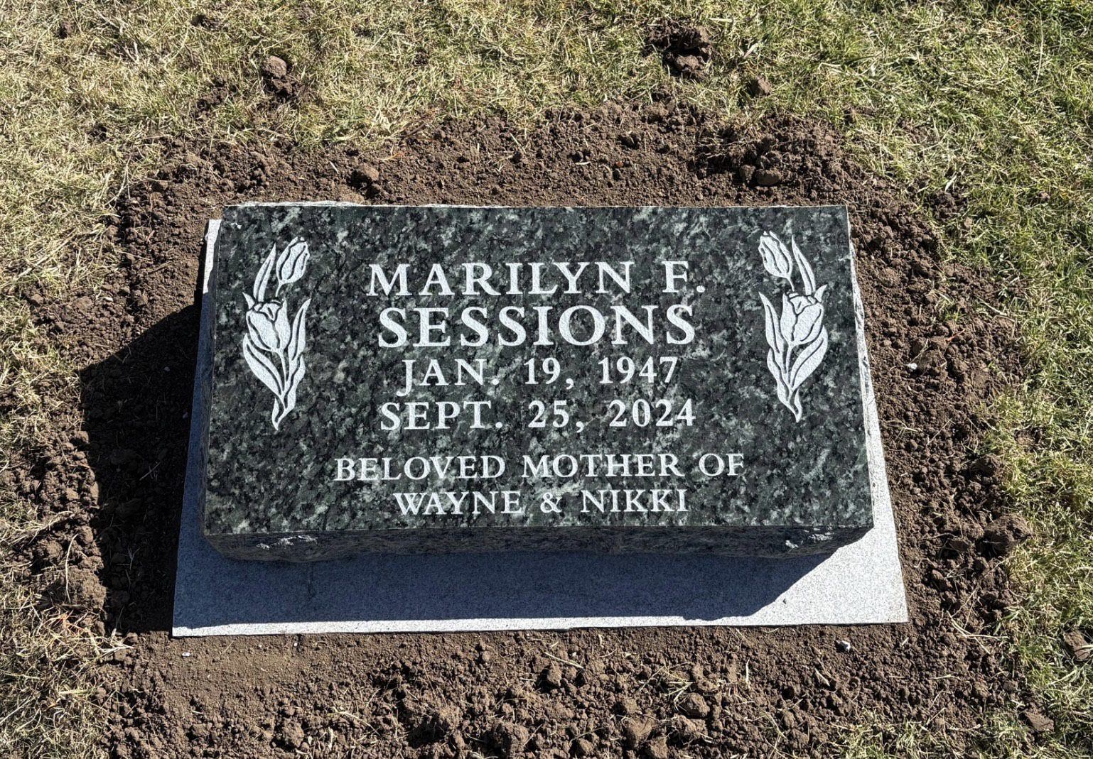 Memorial stone in grassy area.